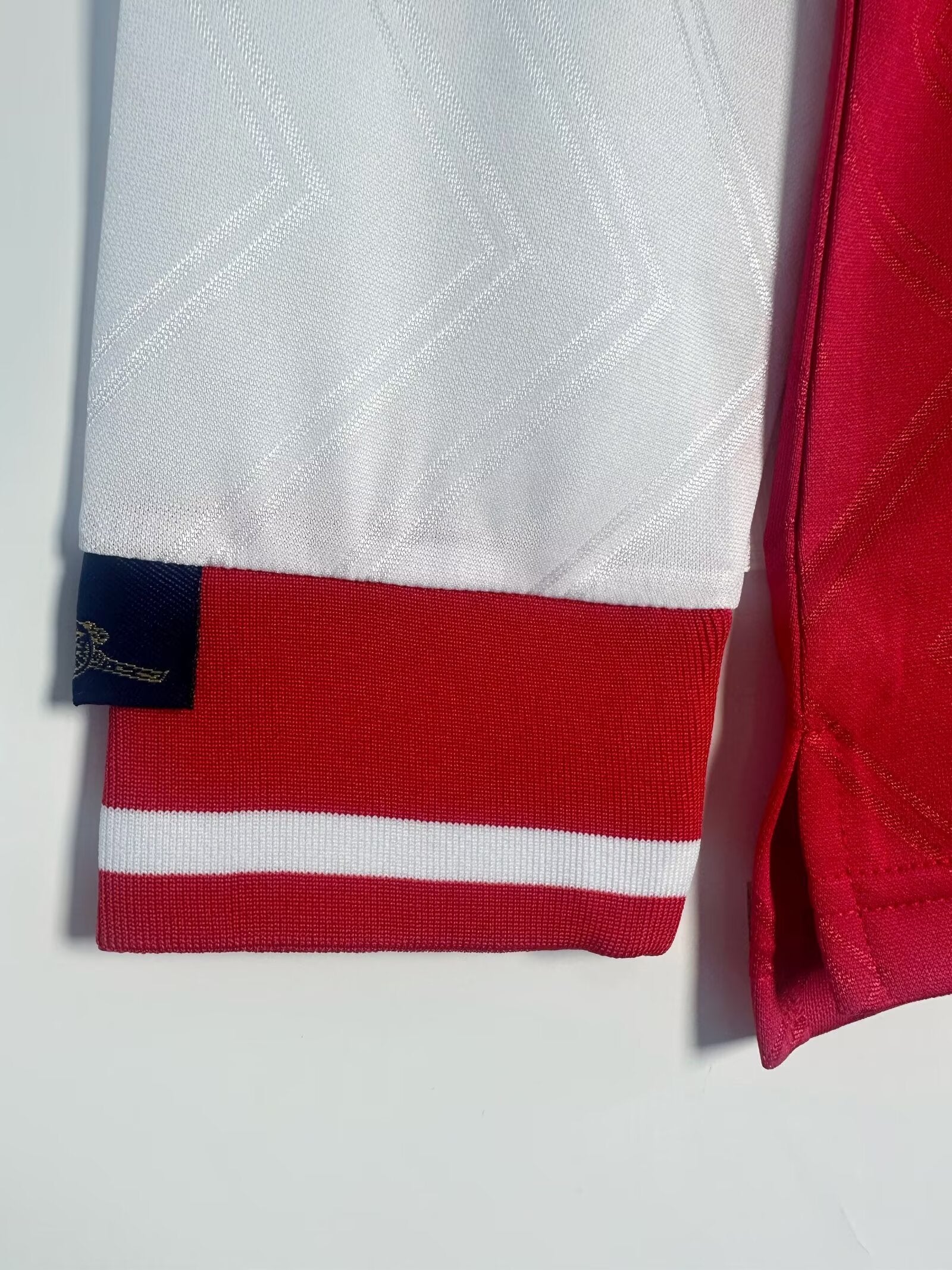 Close-up of a red and white sports jersey with a brand logo on a light gray background