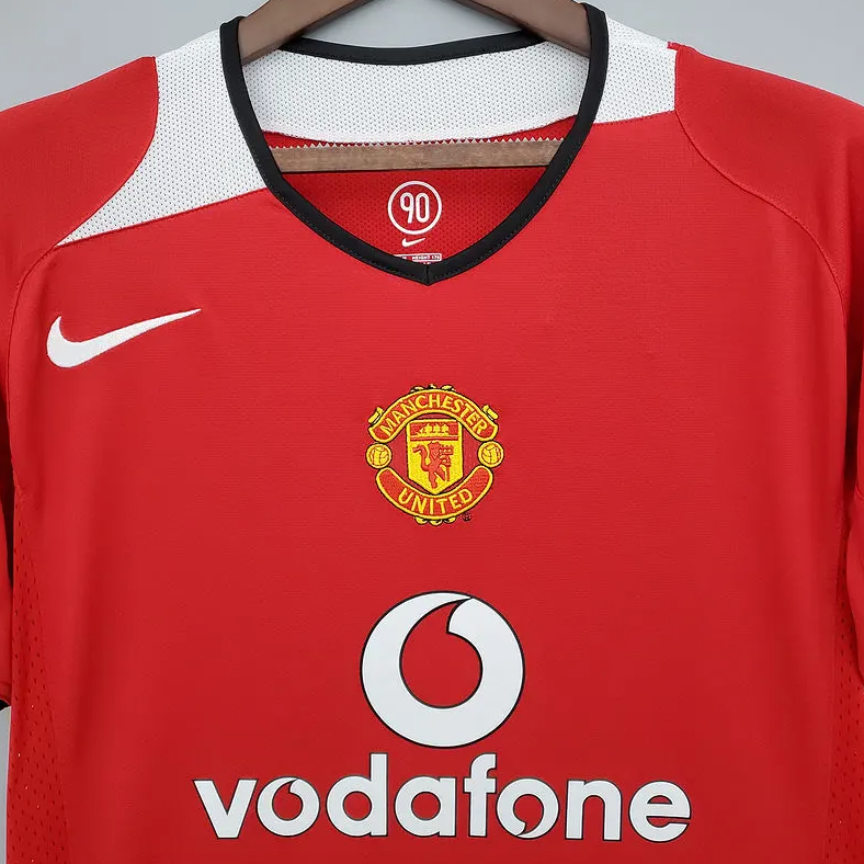 Red Manchester United jersey with Nike and Vodafone logos on a hanger.