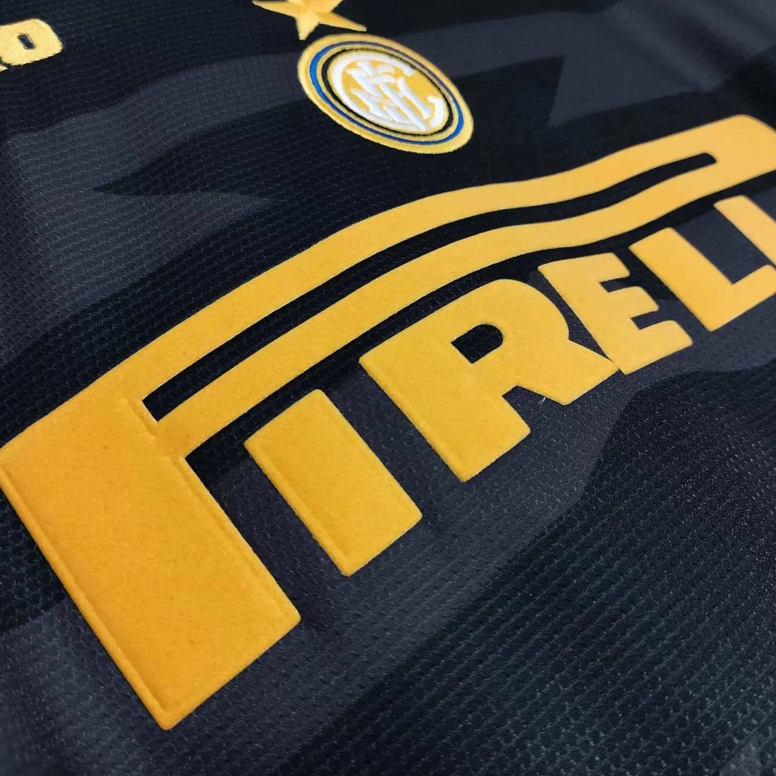 Close-up of a dark navy soccer jersey with a large yellow Pirelli sponsor logo and part of the Inter Milan crest.