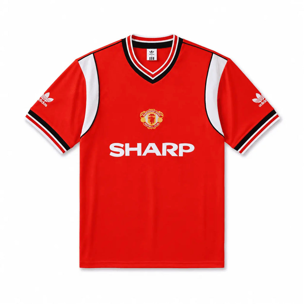 A red short-sleeve Manchester United soccer jersey by Adidas, featuring white side panels, black and white striped collar and sleeve cuffs, the Manchester United crest on the chest, and the white Sharp sponsor logo across the front.