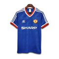 Blue Manchester United jersey with Adidas and Sharp logos on a white background