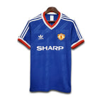Blue Manchester United jersey with Adidas and Sharp logos on a white background