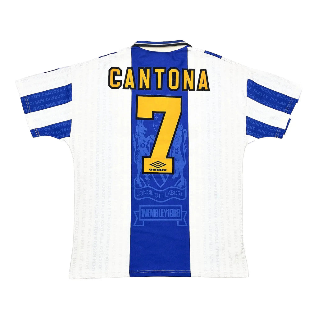 Back view of a white and blue football jersey with 'CANTONA' and the number '7' in yellow, featuring the Umbro logo and Wembley 1980 text.