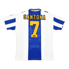 Back view of a white and blue football jersey with 'CANTONA' and the number '7' in yellow, featuring the Umbro logo and Wembley 1980 text.