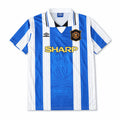 A retro-style football jersey with vertical blue and white stripes, featuring the Umbro logo on the right chest, the Manchester United crest on the left chest, and 'SHARP' in yellow text across the center.