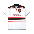White Umbro Manchester United jersey with black and red accents, featuring a logo and text on a white background