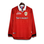 Red Manchester United 1999 UCL jersey with visible SHARP branding on a white background
