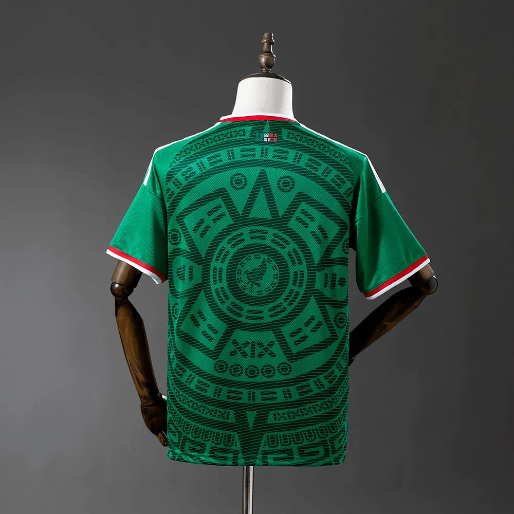 Green sports jersey with intricate patterns on a mannequin against a gray background
