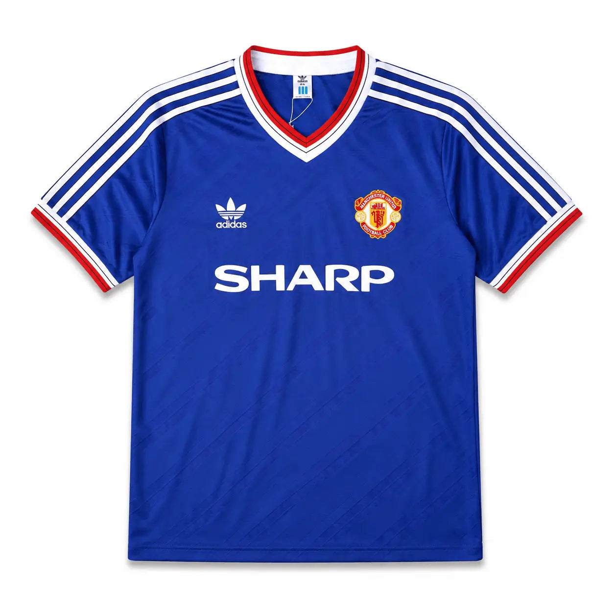 A blue Manchester United football jersey, featuring the club's crest on the left chest, the white Adidas logo on the right chest, and the sponsor 'SHARP' printed in white across the center. The jersey has a V-neck with red and white trim, and white stripes on the shoulders and sleeves.