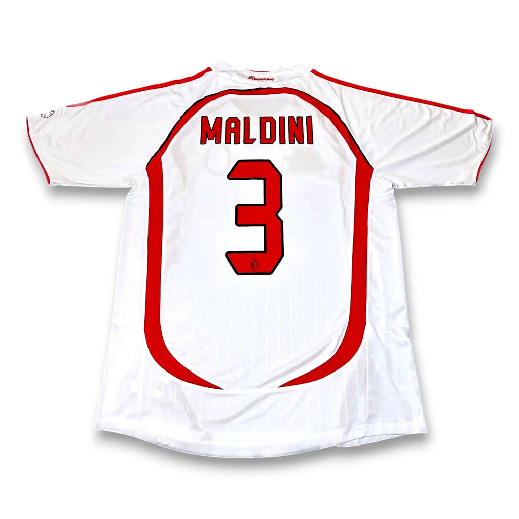 A white soccer jersey shown from the back, featuring the name 'MALDINI' and the number '3' in red with black outlines. The jersey has red trim along the shoulders and sides, set against a plain white background.