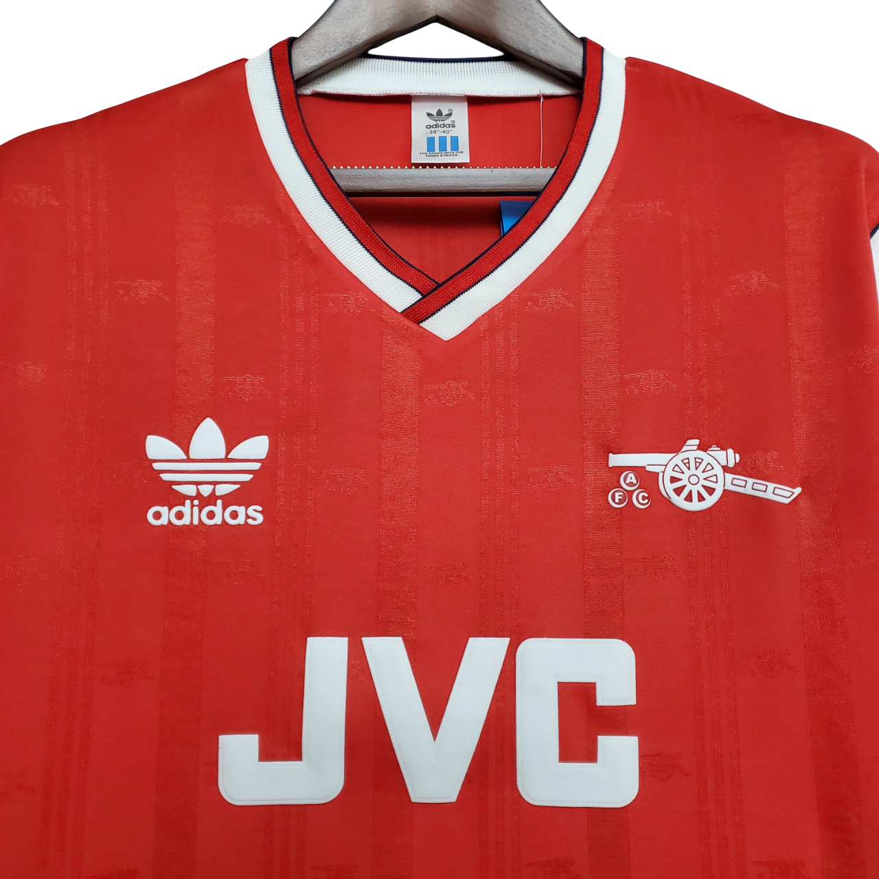 Red Arsenal jersey with Adidas logo and JVC branding on a hanger
