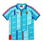 A light blue and cyan FC Barcelona soccer jersey with a repeating white 'Barça' logo pattern, featuring the club crest on the right chest and the Kappa logo on the left chest. The jersey has a V-neck collar, short sleeves with red and black striped shoulder details, and red and blue trim.
