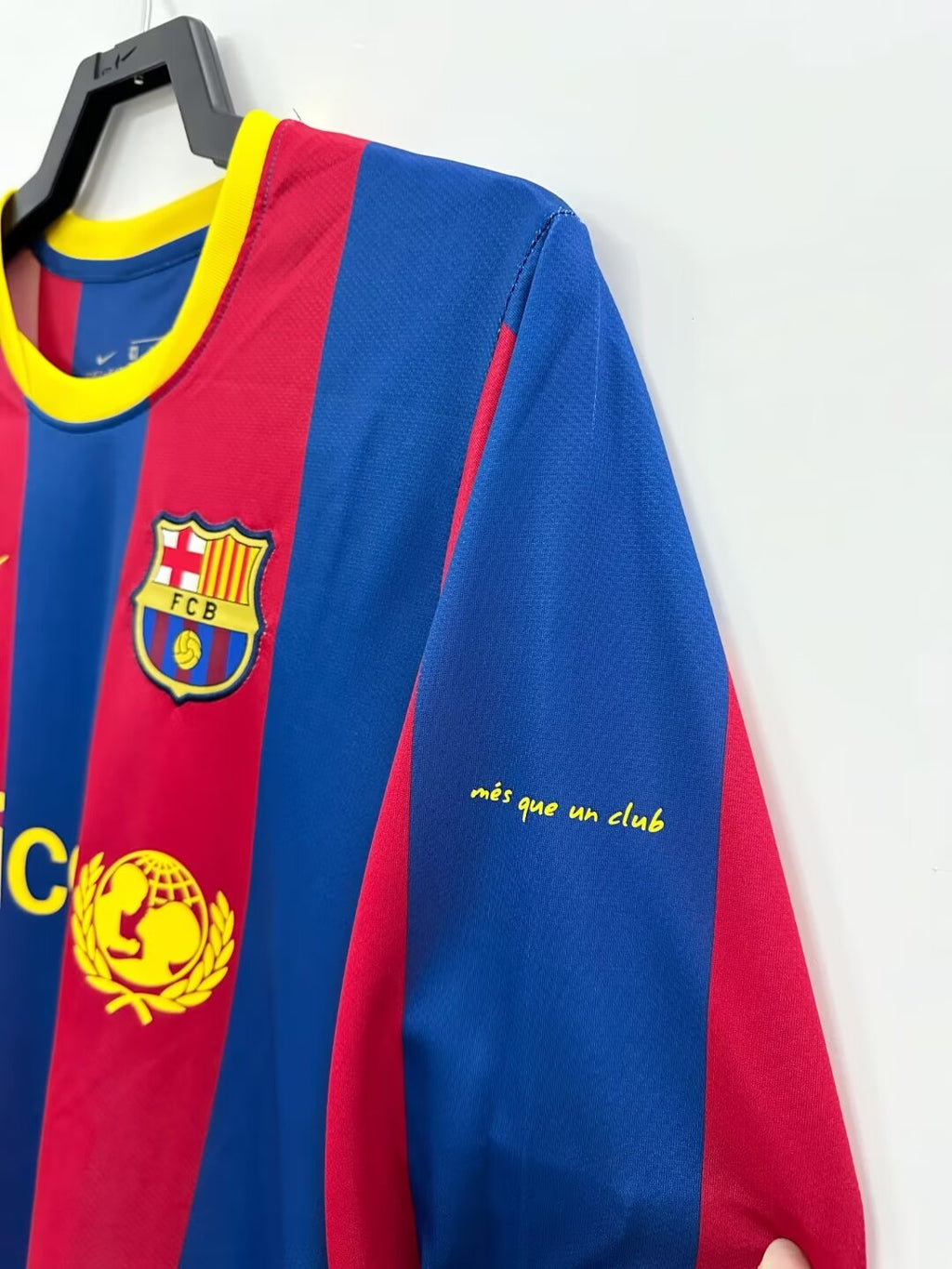 Red and blue sports jersey with FC Barcelona logo on a hanger against a white background