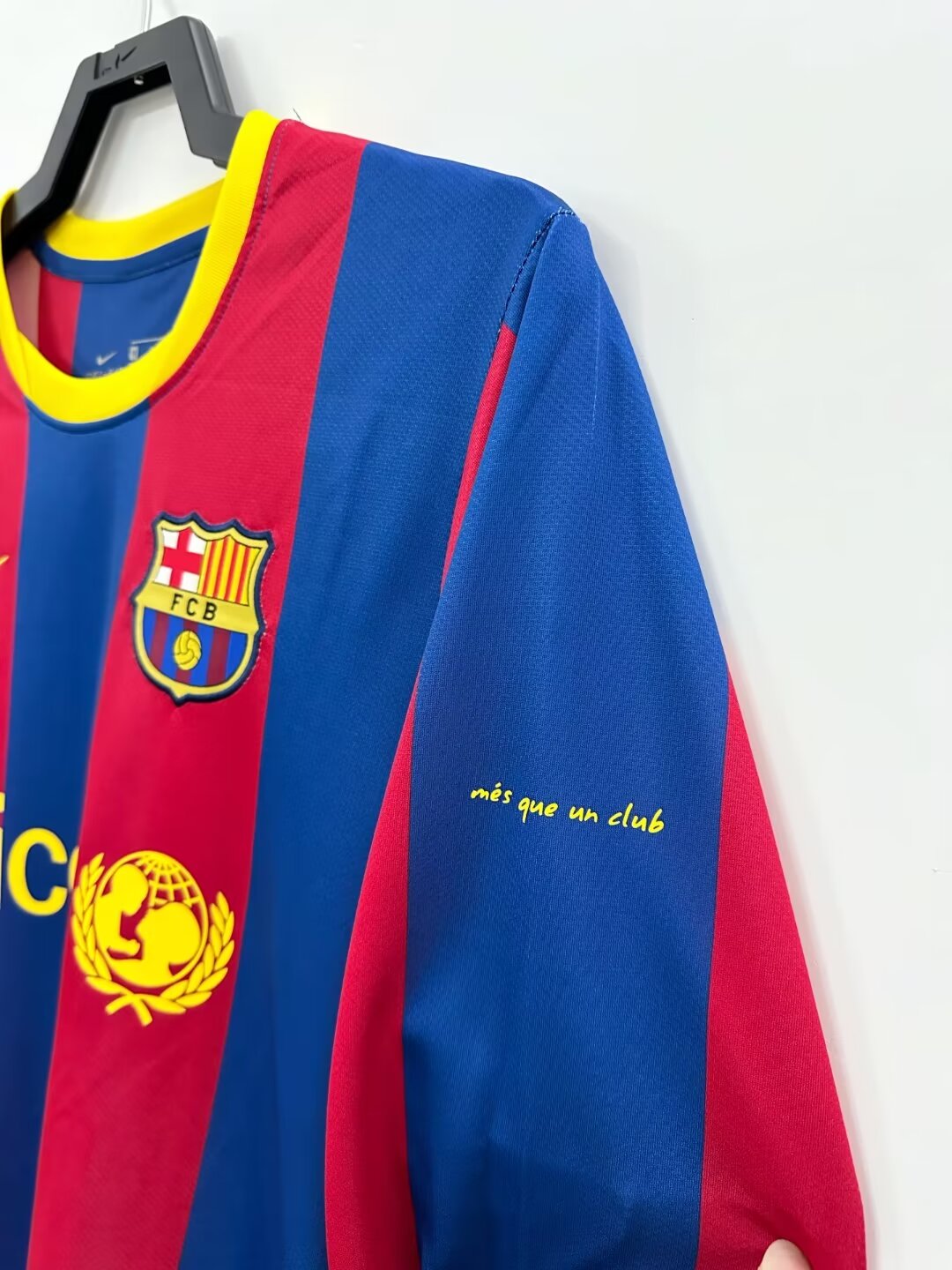 Red and blue sports jersey with FC Barcelona logo on a hanger against a white background