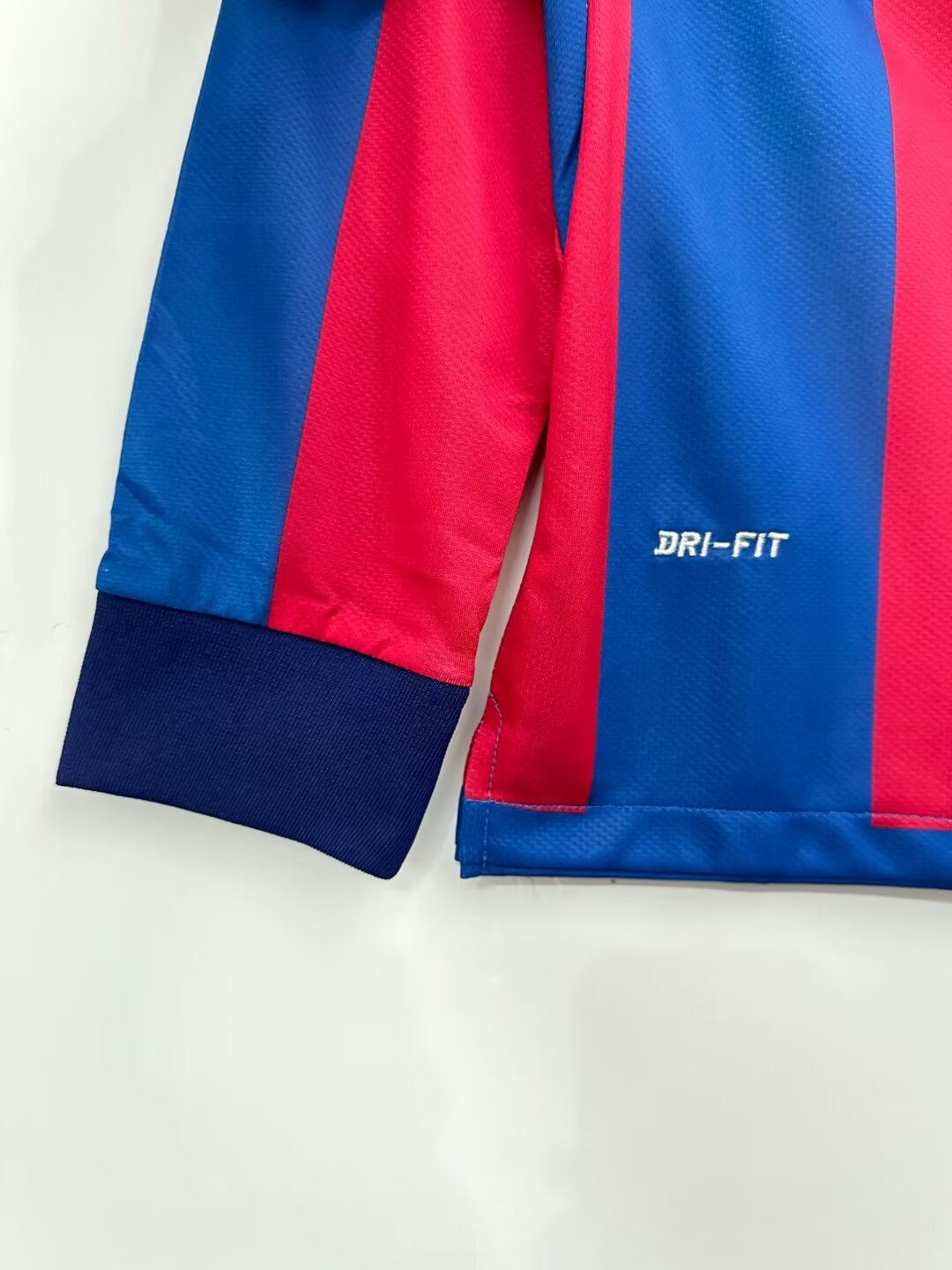 Close-up of a blue and red sports jersey with 'Dri-FIT' branding on a white background