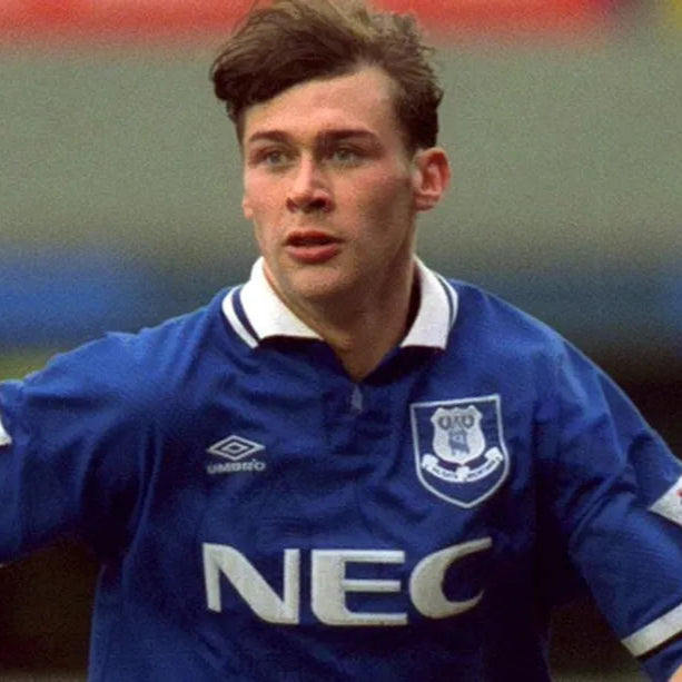 Ferguson wearing a blue sports jersey with a logo and text, standing on a field.