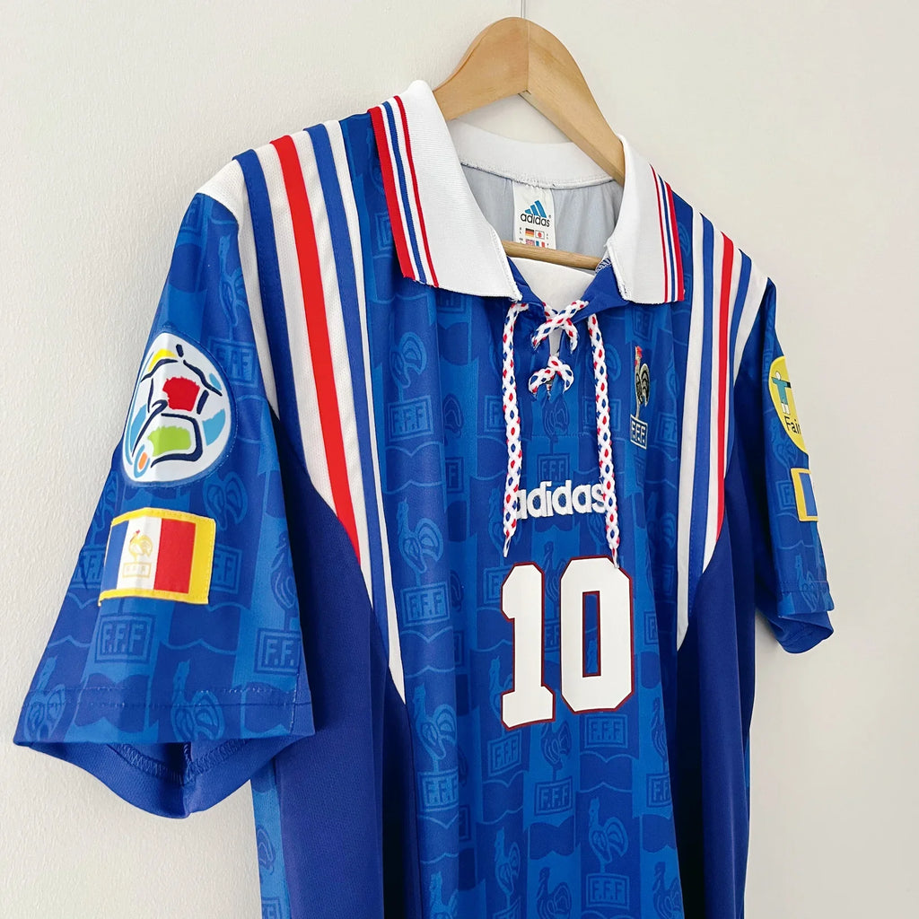 Blue sports jersey with red and white stripes on a hanger against a white background