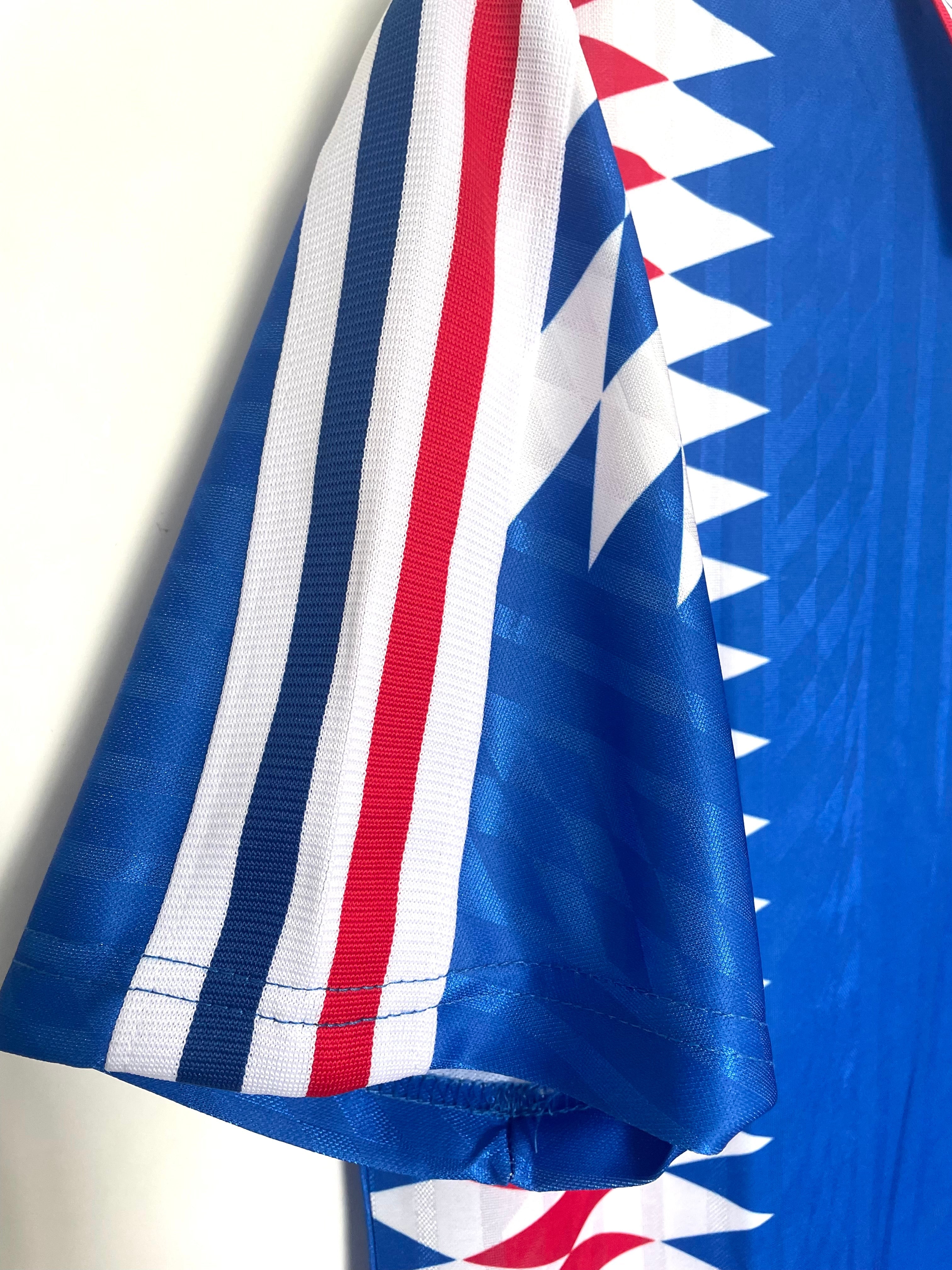 Close-up of a blue sports jersey with white and red accents on a plain background