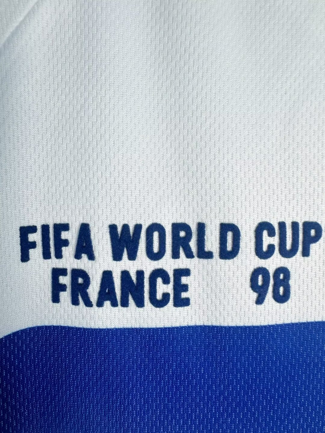 Text 'FIFA World Cup France 98' on a sports jersey with blue and white colors.