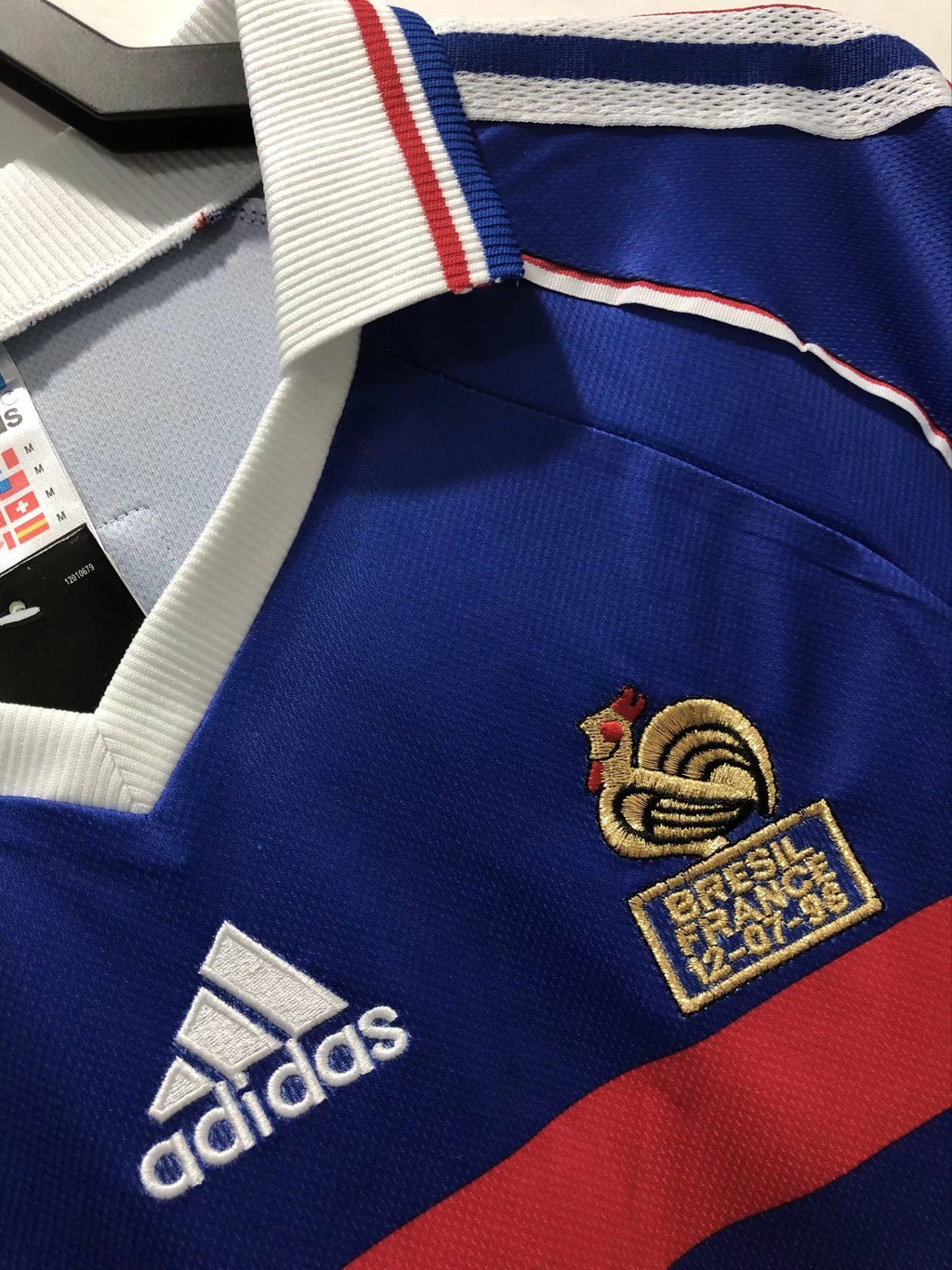 Close-up of a blue sports jersey with Adidas logo and French football federation emblem.