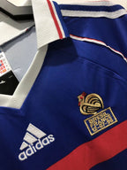 Close-up of a blue sports jersey with Adidas logo and French football federation emblem.