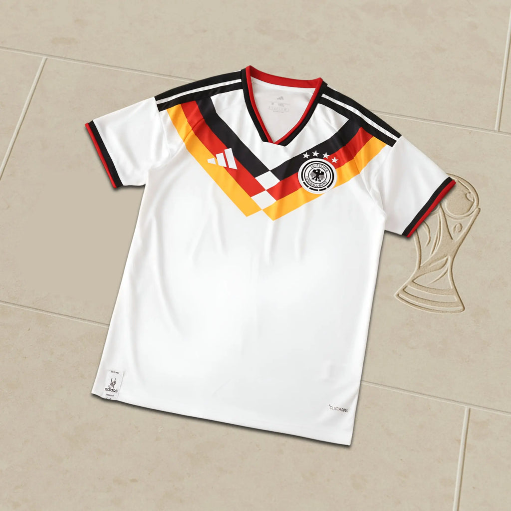 White Germany World Cup sports jersey with red, yellow, and black design on a beige surface