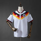White Germany jersey with red, yellow, and black design on a mannequin against a dark background