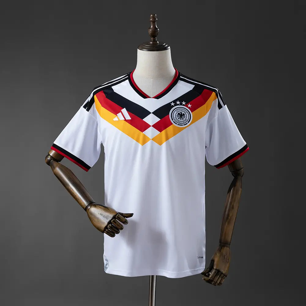 White Germany jersey with red, yellow, and black design on a mannequin against a dark background