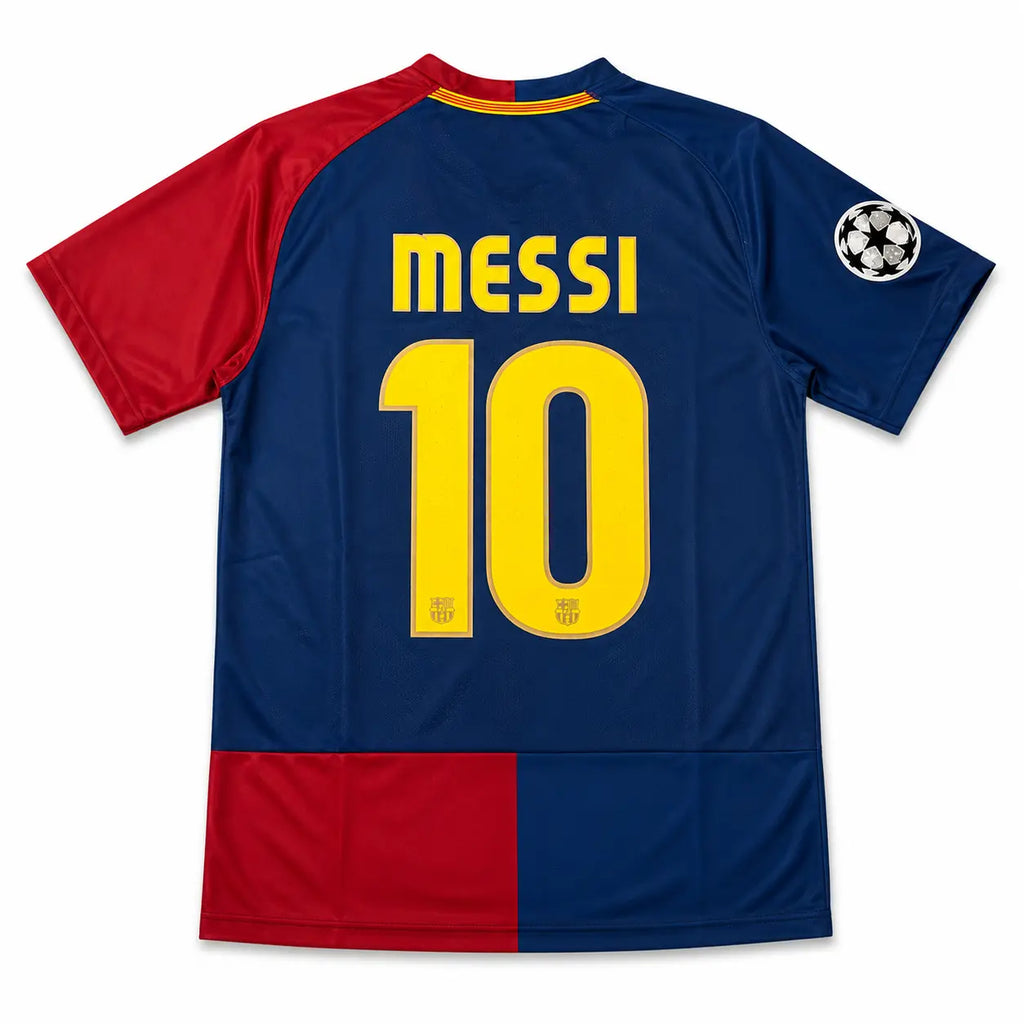 Back view of a soccer jersey with 'MESSI' and the number '10' in yellow on a navy blue background, with red sleeves and a red block at the bottom, plus a Champions League patch on the right shoulder.