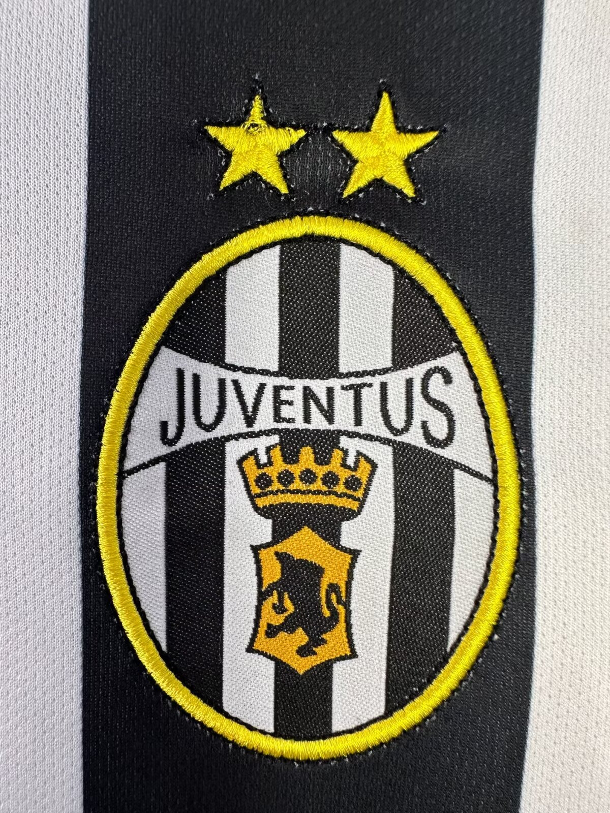 Juventus logo on a sports jersey with black and white stripes.