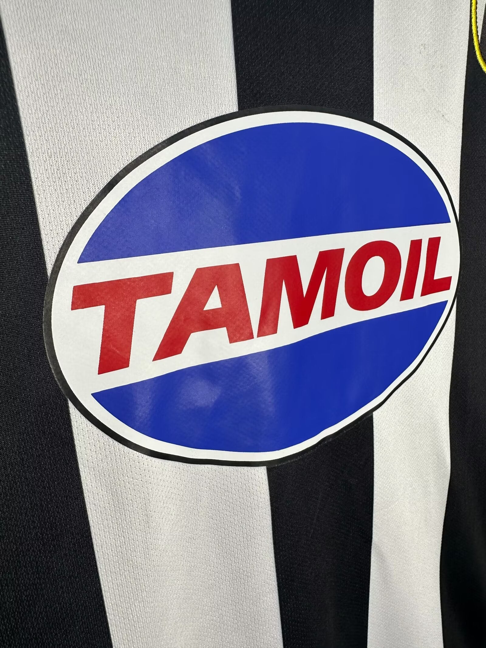 Tamoil logo on a sports jersey with black and white stripes