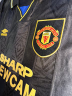 Manchester United Logo stitched on black shirt.