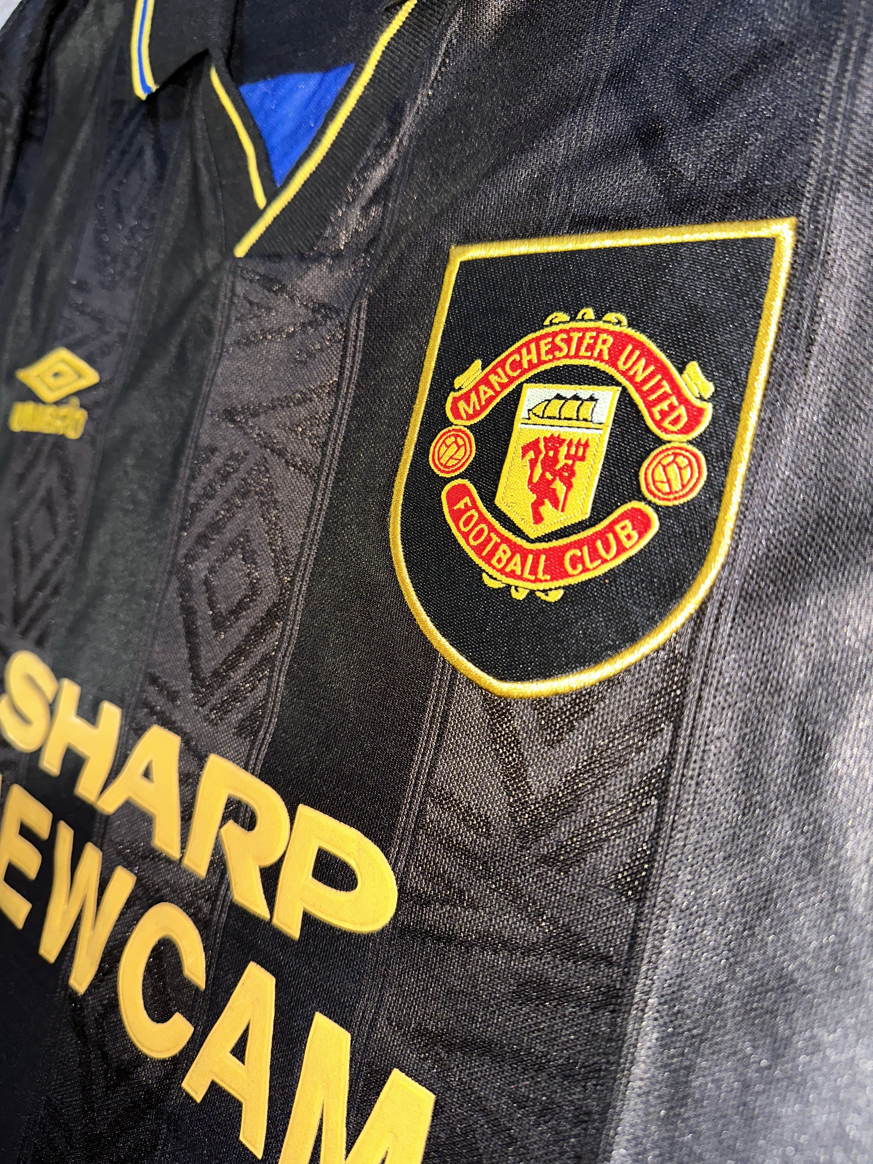 Manchester United Logo stitched on black shirt.
