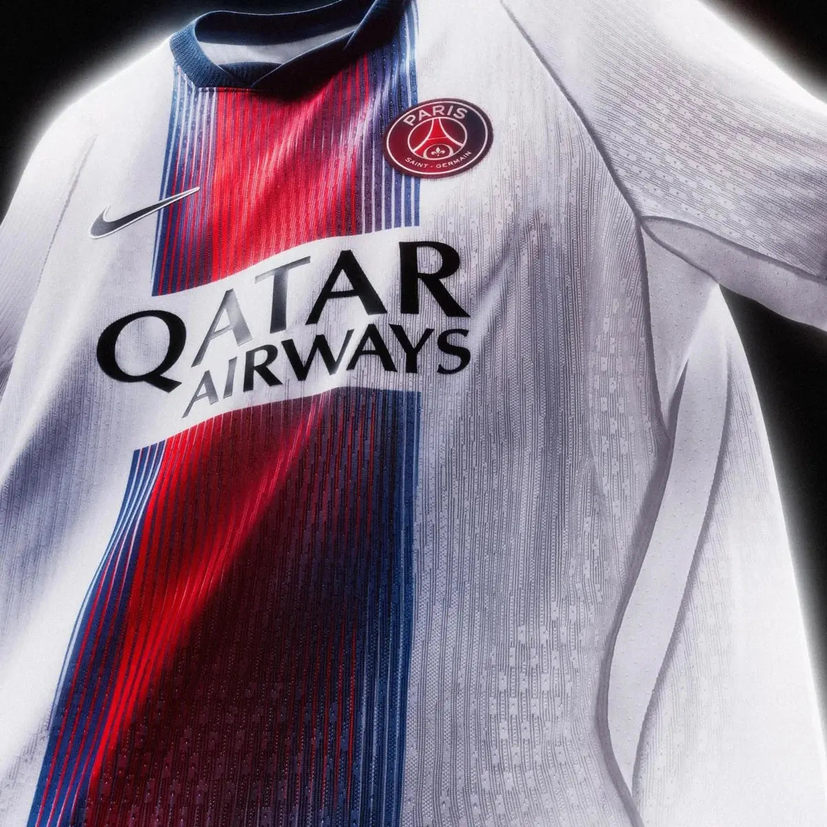 A close-up of a Paris Saint-Germain soccer jersey with a white textured body, a vertical red and navy blue stripe down the center, the PSG crest on the chest, a Nike swoosh, and the Qatar Airways sponsor logo.
