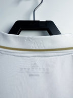 White shirt with a gold trim on a hanger against a white background