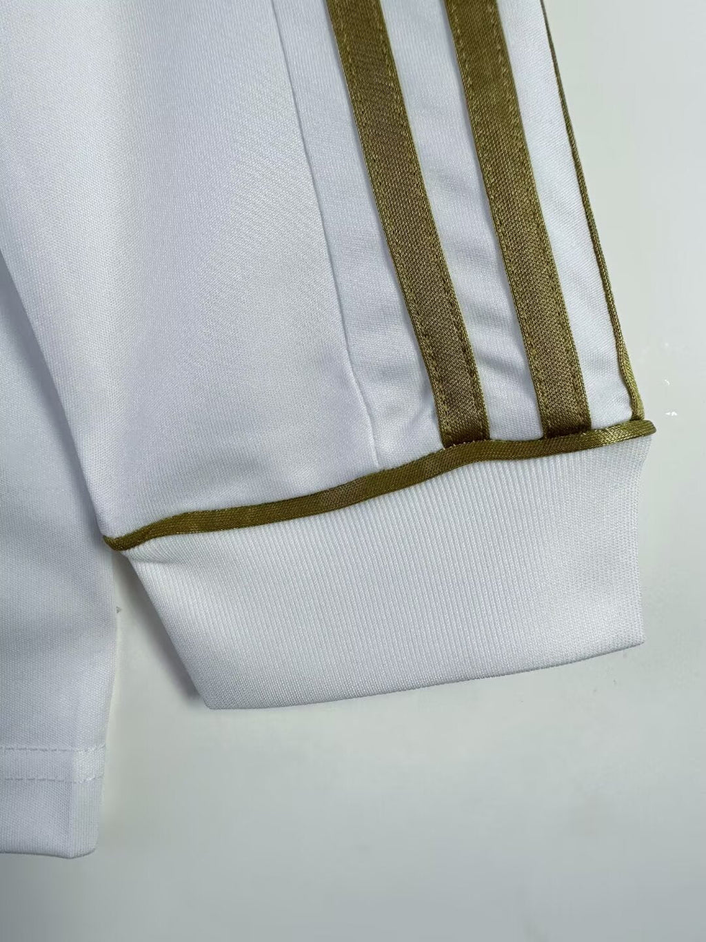 Close-up of a white garment with brown trim on a light gray background