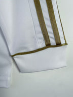 Close-up of a white garment with brown trim on a light gray background