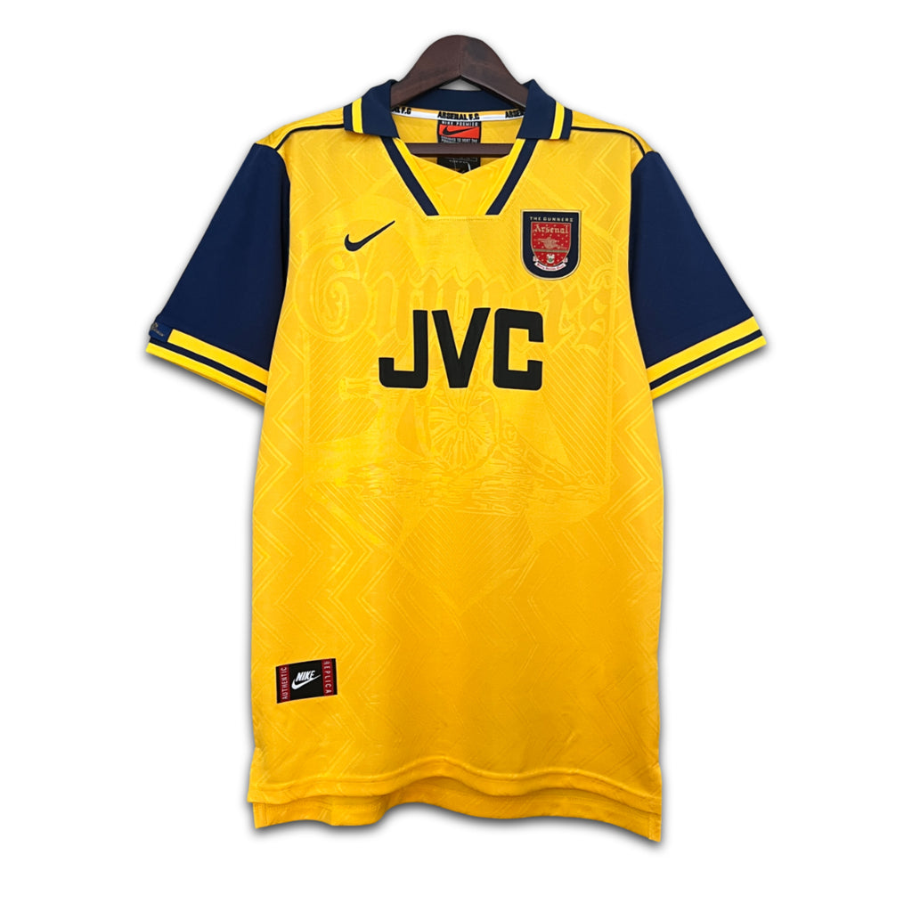 Yellow Arsenal jersey with navy sleeves and 'JVC' branding on a white background