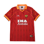 A red AS Roma soccer jersey by Diadora, featuring the white 'INA Assitalia' sponsor logo on the chest, the club crest, and orange accents on the collar and sleeve cuffs, displayed against a solid white background.
