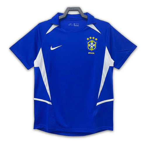 A blue soccer jersey with white accents, featuring the Brazil national team crest, displayed on a white background.