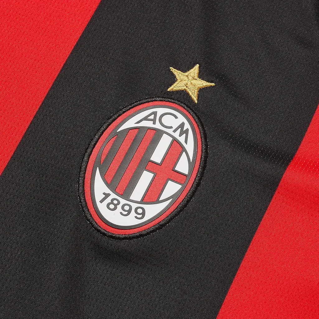 AC Milan logo on a black and red sports jersey with a gold star above it.