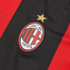 AC Milan logo on a black and red sports jersey with a gold star above it.