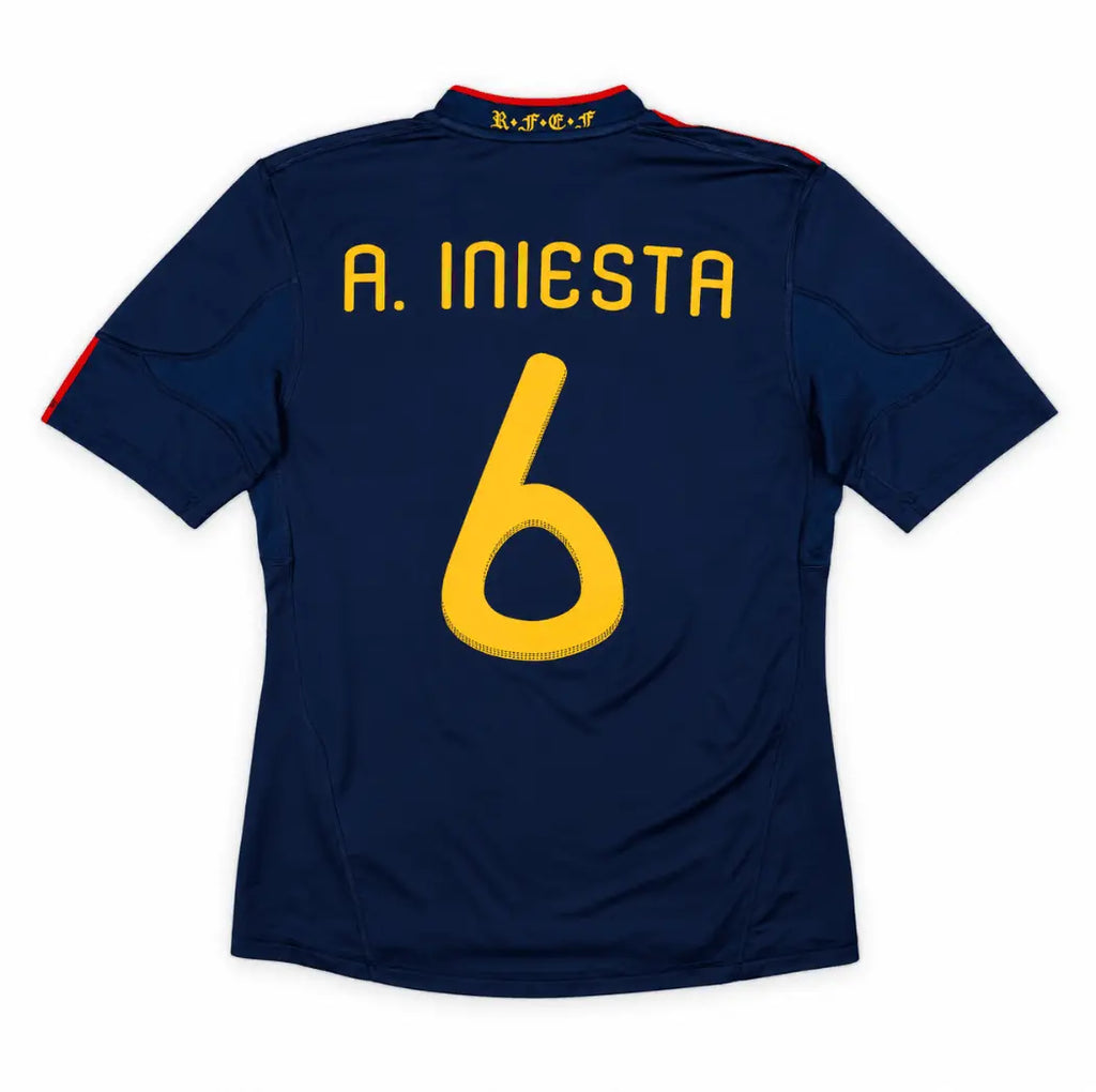 Back view of a navy blue short-sleeve soccer jersey with 'A. INIESTA' and the number '6' in yellow on the back, shown on a plain white background.