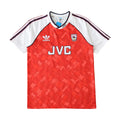 A vintage Adidas Arsenal home soccer jersey from the 1990-2000 era, featuring a red body with a subtle geometric pattern, white sleeves, and navy stripes on the shoulders. The front displays 'JVC' sponsor branding in white, the Adidas logo, and the Arsenal crest.