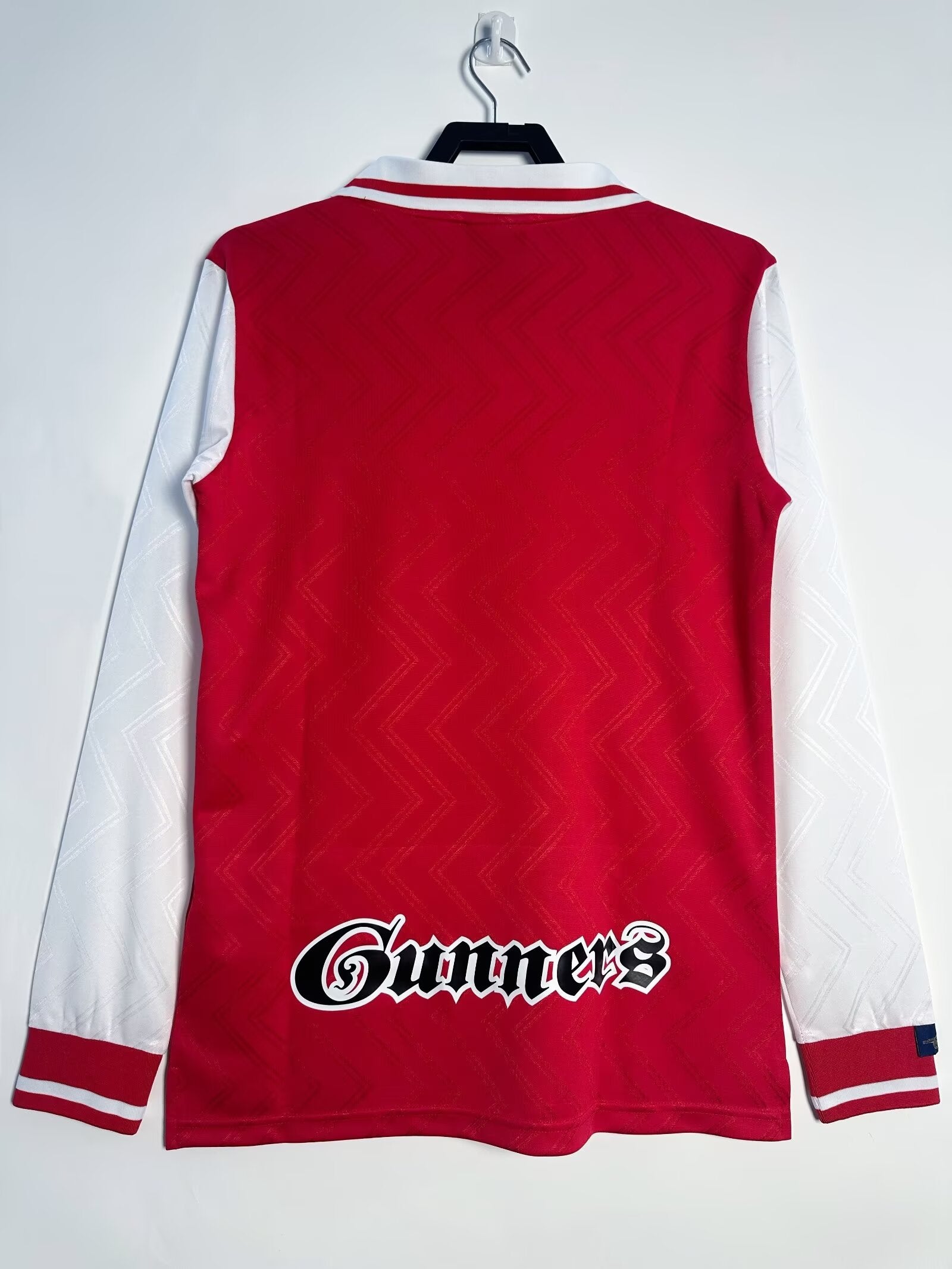 Red and white sports jersey with 'Gunners' logo on a white background