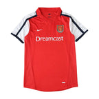 A red Nike Arsenal short-sleeve soccer jersey with white and navy blue sleeve stripes, featuring the 'Dreamcast' sponsor logo on the chest.