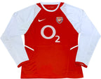 Red and white sports jersey with Arsenal logo and Nike branding on a green background