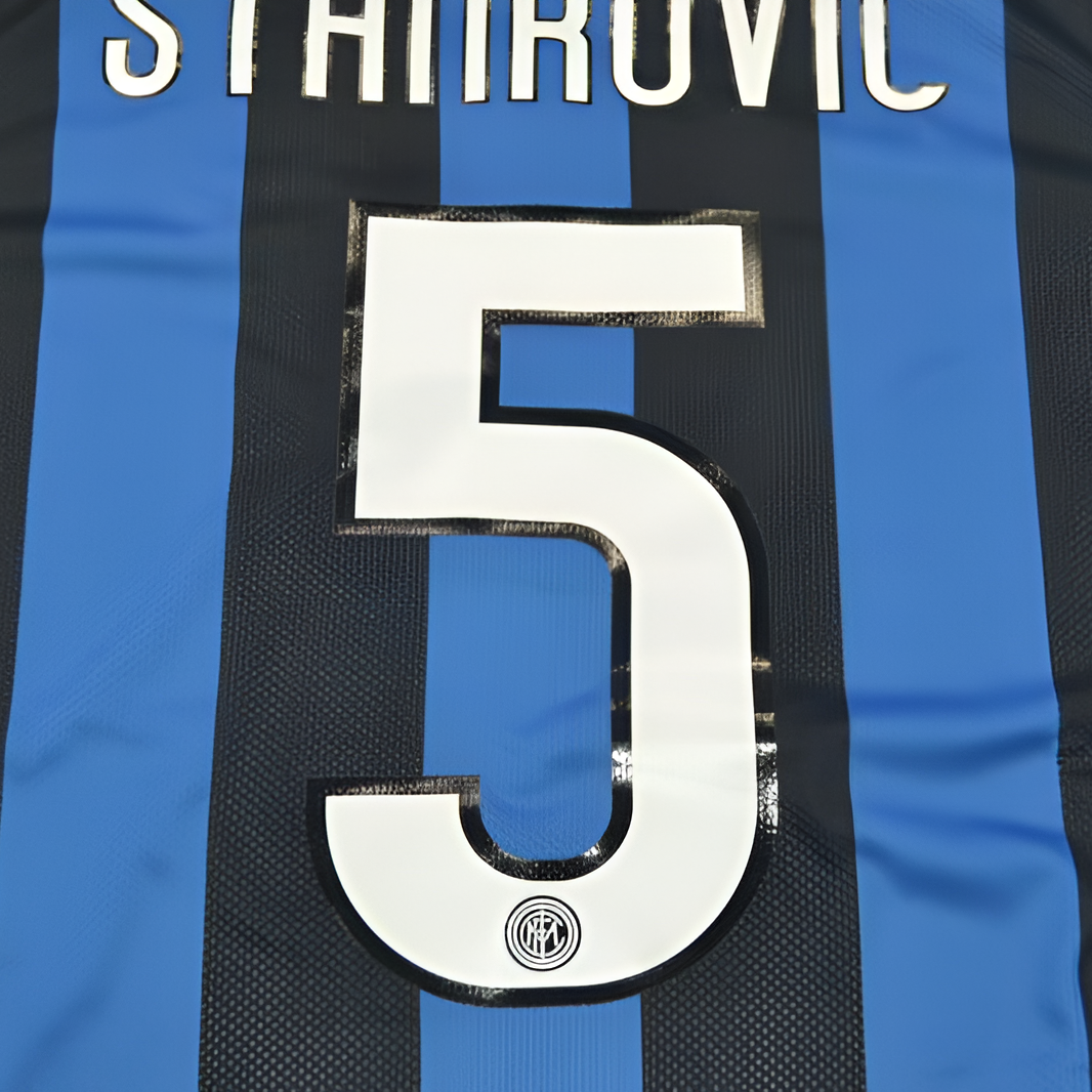Close-up of the back of a black and blue striped soccer jersey with the name STANROVIC and the number 5 in white.