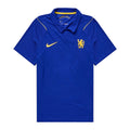 A royal blue Chelsea FC short-sleeve polo shirt by Nike, featuring a yellow Nike swoosh on the right chest and the Chelsea crest on the left chest, displayed against a solid white background.