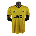 Yellow sports jersey with Adidas and Arsenal FC logos on a mannequin against a white background
